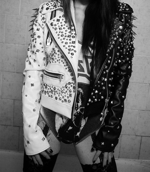 Woman wearing a split black and white studded punk leather jacket with heavy silver spikes and studs.